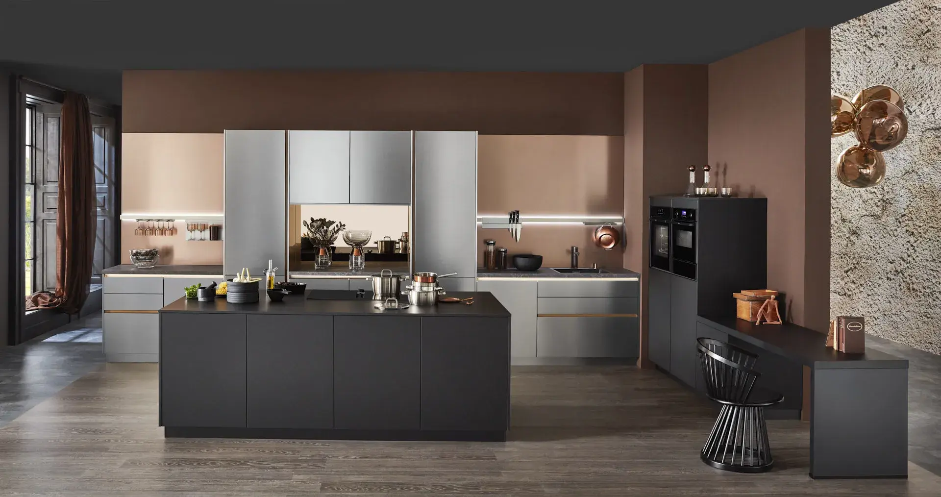 Hauptschuss, Mix aus Keramik und Bronzenachbildung, Kücheninsel mit NEFF Induktionskochfeld und Muldenlüfter, schwarzer Schrank, Edelstahlfronten, Bronze Nischenrückwand, 2 NEFF Einbaubacköfen, Messing Spüle